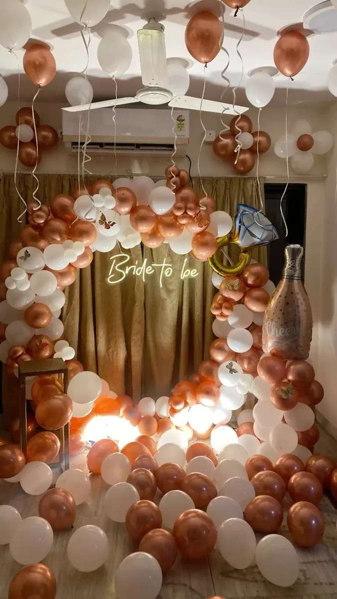 Bridal shower at home with rose-gold and white balloons, a Bride to Be neon sign and a ring balloon