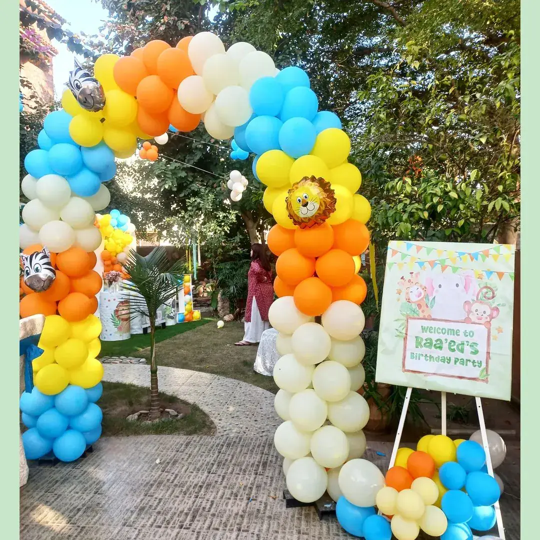 Children's birthday safari balloon arch in orange, yellow, blue and cream beside a welcome sign — Baraka Events, Lahore