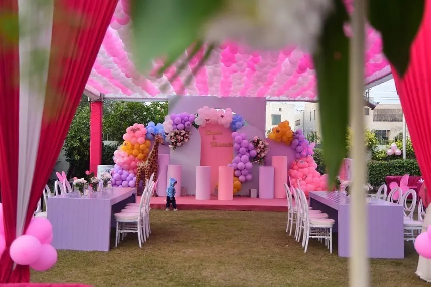 Children's birthday with a pastel pink and purple balloon backdrop, giraffe figure and balloon-covered ceiling
