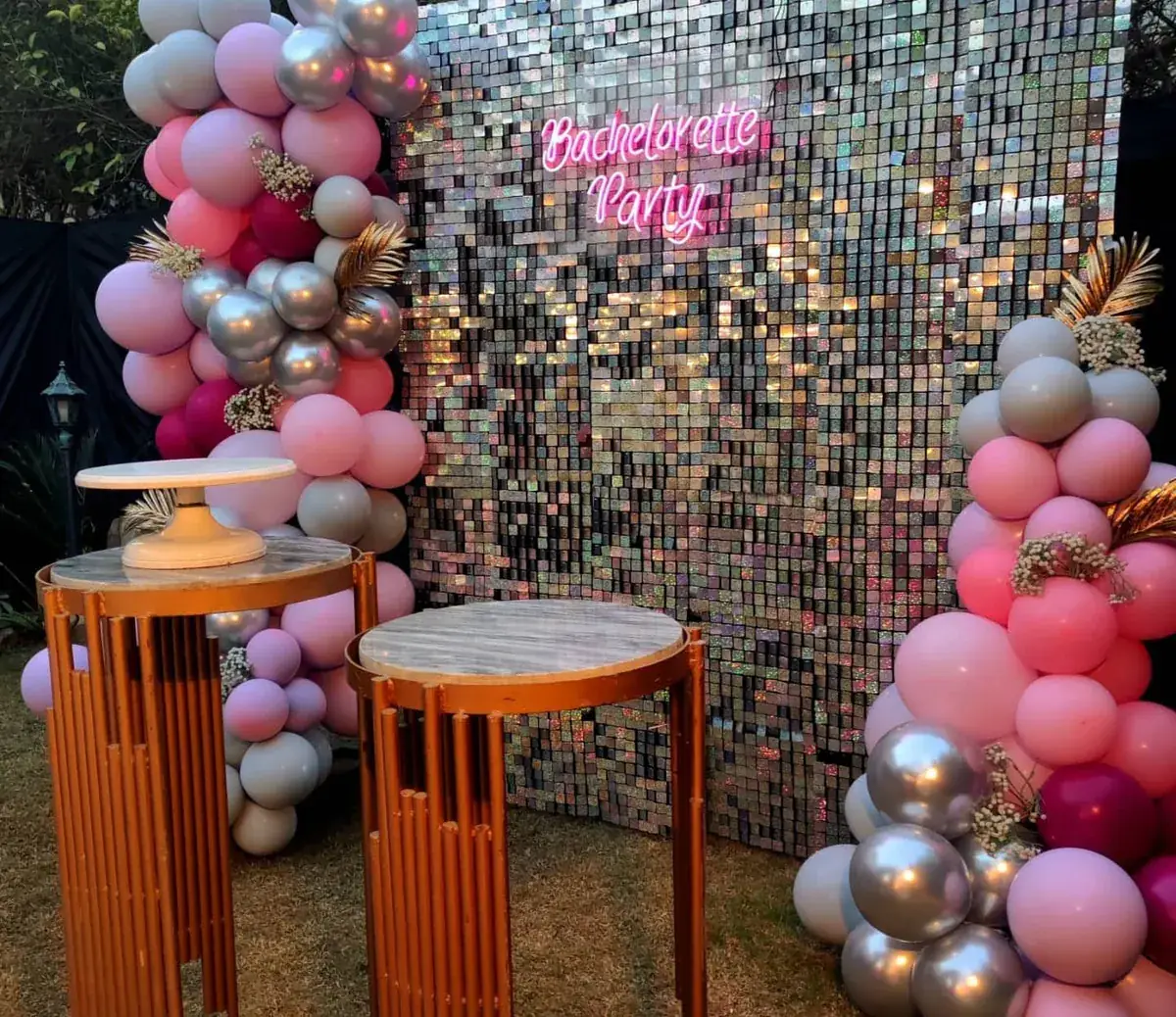 Bachelorette party backdrop with a sequin wall, neon sign, pink and silver balloons and copper tables