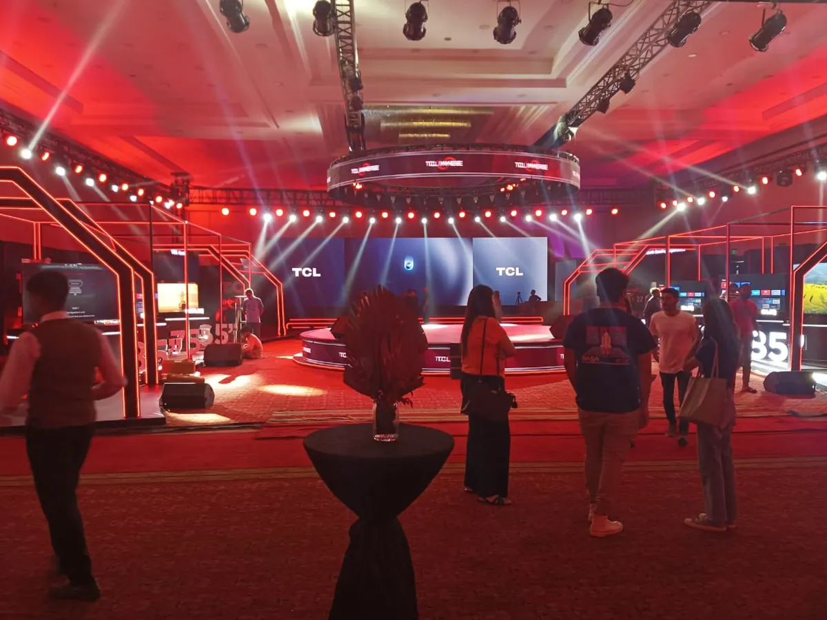 Event hall with red truss arches, LED screens and a circular central platform