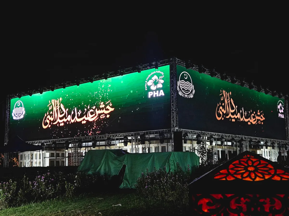 Close night view of an outdoor LED screen rig with a calligraphy greeting and a lantern in the foreground