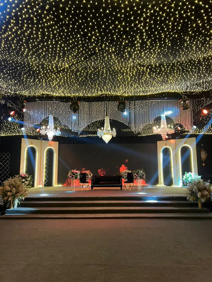 Evening stage under a fairy-light canopy with chandeliers and lit arched frames