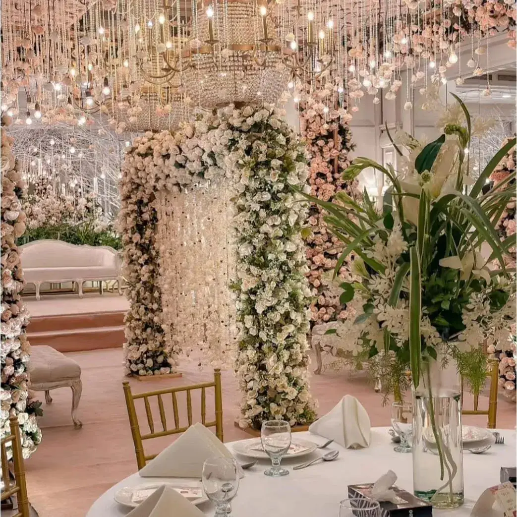 Walima floral arch of white and blush roses under hanging bead garlands and crystal chandeliers — Baraka Events, Lahore