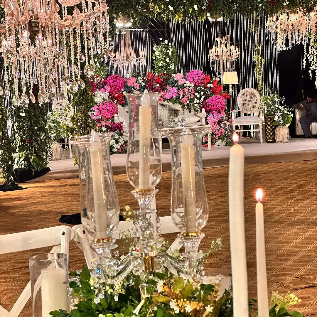 Baraat stage with candles in glass holders before pink and magenta flowers and chandeliers — Baraka Events, Lahore